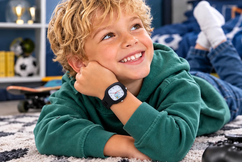 Un garçon allongé sourit avec la montre noire au poignet
